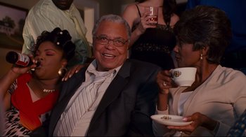 Movie still from “Welcome Home, Roscoe Jenkins” (2008), directed by Malcolm D. Lee – An older man sitting next to a woman holding a cup; Medium shot, Over the shoulder angle