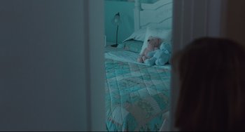 Movie still from “Welcome to the Rileys” (2010), directed by Jake Scott – A bed with a blue quilt and a teddy bear on top of it; Medium shot, High angle