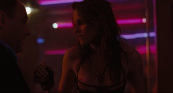 Movie still from “Welcome to the Rileys” (2010), directed by Jake Scott – A beautiful woman in a black bikini standing in front of neon lights; Medium shot, Over the shoulder angle