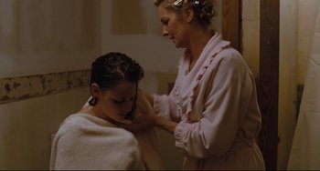 Movie still from “Welcome to the Rileys” (2010), directed by Jake Scott – A woman in a pink bathrobe is getting her hair combed by a woman in a pink bathrobe; Medium shot, High angle