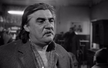 Movie still from “Werckmeister Harmonies” (2000), directed by Ágnes Hranitzky – An older man with long hair wearing a jacket; Close Up shot, Low angle