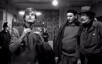 Movie still from “Werckmeister Harmonies” (2000), directed by Ágnes Hranitzky – A group of people standing next to each other in a room; Medium shot, Over the shoulder angle