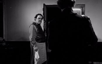 Movie still from “Werckmeister Harmonies” (2000), directed by Ágnes Hranitzky – A black and white photo of a man holding a towel; Medium shot, Over the shoulder angle
