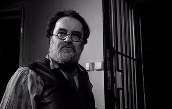 Movie still from “Werckmeister Harmonies” (2000), directed by Ágnes Hranitzky – A man with a beard and glasses in front of a jail cell; Close Up shot, Low angle
