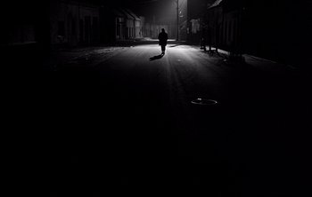 Movie still from “Werckmeister Harmonies” (2000), directed by Ágnes Hranitzky – A person standing in the middle of a street at night; Extreme Wide shot, Low angle