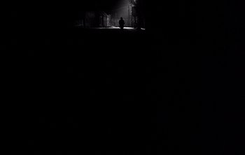 Movie still from “Werckmeister Harmonies” (2000), directed by Ágnes Hranitzky – A person sitting on the ground in the dark; Extreme Wide shot, High angle