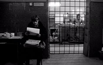 Movie still from “Werckmeister Harmonies” (2000), directed by Ágnes Hranitzky – A woman sitting at a table with a stack of papers; Wide shot, Low angle