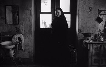 Movie still from “Werckmeister Harmonies” (2000), directed by Ágnes Hranitzky – A woman standing in front of an open window; Medium shot, Low angle