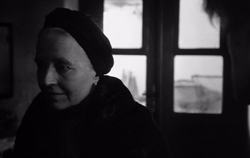 Movie still from “Werckmeister Harmonies” (2000), directed by Ágnes Hranitzky – An older woman wearing a black hat and a black coat; Close Up shot, Over the shoulder angle