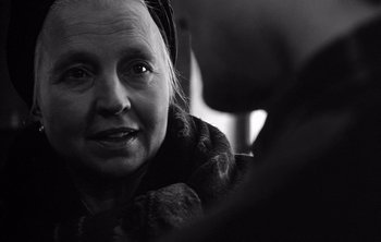 Movie still from “Werckmeister Harmonies” (2000), directed by Ágnes Hranitzky – An older woman with a large smile on her face; Close Up shot, Over the shoulder angle