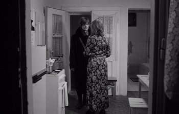Movie still from “Werckmeister Harmonies” (2000), directed by Ágnes Hranitzky – Two people standing in a kitchen talking to each other; Medium shot, Over the shoulder angle