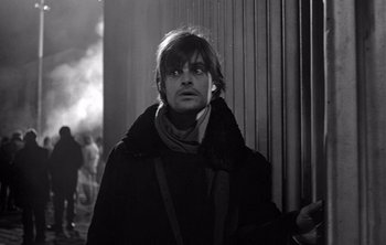 Movie still from “Werckmeister Harmonies” (2000), directed by Ágnes Hranitzky – A black and white photo of a man in a black coat; Close Up shot, Over the shoulder angle