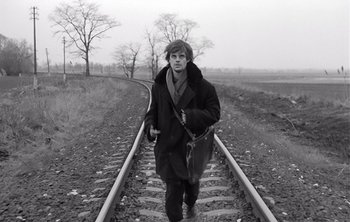 Movie still from “Werckmeister Harmonies” (2000), directed by Ágnes Hranitzky – A man walking down a train track in the snow; Medium shot, High angle