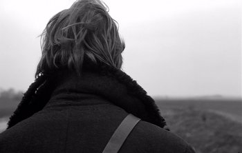 Movie still from “Werckmeister Harmonies” (2000), directed by Ágnes Hranitzky – A woman wearing a coat and a fur coat; Close Up shot, Over the shoulder angle