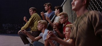 Movie still from “West Side Story” (1961), directed by Jerome Robbins – A group of young men sitting on a bench; Medium shot, High angle