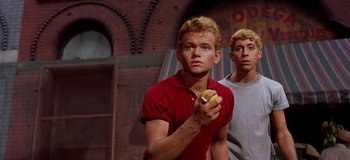 Movie still from “West Side Story” (1961), directed by Jerome Robbins – A man holding an object in front of another man; Medium shot, Low angle