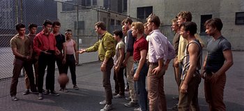 Movie still from “West Side Story” (1961), directed by Jerome Robbins – A group of men standing in front of a fence; Wide shot, High angle