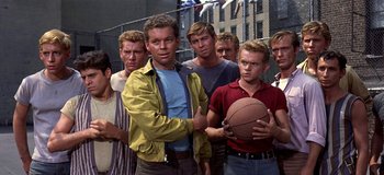Movie still from “West Side Story” (1961), directed by Jerome Robbins – A group of men standing next to each other holding a basketball; Medium shot, Low angle