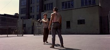 Movie still from “West Side Story” (1961), directed by Jerome Robbins – Two young men standing on a street corner holding hands; Wide shot, Over the shoulder angle