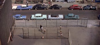 Movie still from “West Side Story” (1961), directed by Jerome Robbins – An aerial view of a street with cars parked on the side of the road; Extreme Wide shot, High angle