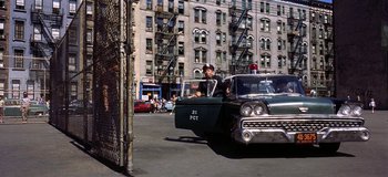Movie still from “West Side Story” (1961), directed by Jerome Robbins – A man sitting in the back of an old car; Wide shot, Over the shoulder angle
