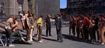 Movie still from “West Side Story” (1961), directed by Jerome Robbins – A group of people standing around a building; Wide shot, Over the shoulder angle
