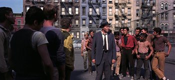 Movie still from “West Side Story” (1961), directed by Jerome Robbins – A group of people standing around a building; Wide shot, Over the shoulder angle