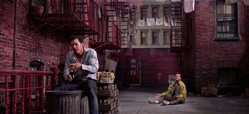 Movie still from “West Side Story” (1961), directed by Jerome Robbins – Two men sitting on the side of a fire escape; Wide shot, Low angle