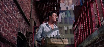 Movie still from “West Side Story” (1961), directed by Jerome Robbins – A man carrying a crate of soda bottles; Medium shot, Low angle