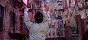 Movie still from “West Side Story” (1961), directed by Jerome Robbins – A man with his hands up in the air; Medium shot, Low angle