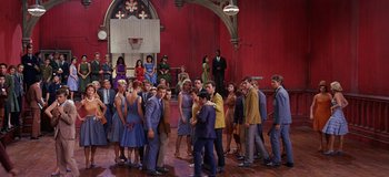 Movie still from “West Side Story” (1961), directed by Jerome Robbins – A group of people standing around each other in a room; Wide shot, High angle