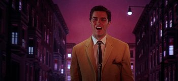 Movie still from “West Side Story” (1961), directed by Jerome Robbins – A man in a suit and tie standing in front of a building; Medium shot, Low angle