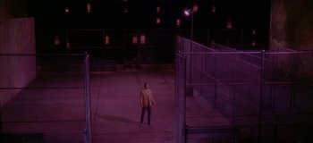 Movie still from “West Side Story” (1961), directed by Jerome Robbins – A man in a suit standing in a parking lot at night; Extreme Wide shot, High angle