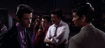 Movie still from “West Side Story” (1961), directed by Jerome Robbins – A group of men standing next to each other in a room; Medium shot, Over the shoulder angle