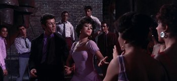 Movie still from “West Side Story” (1961), directed by Jerome Robbins – A group of men and women standing around a woman; Medium shot, Low angle