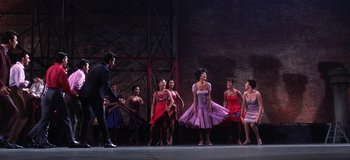 Movie still from “West Side Story” (1961), directed by Jerome Robbins – A group of women in dresses standing on a stage; Wide shot, Low angle