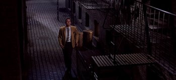 Movie still from “West Side Story” (1961), directed by Jerome Robbins – A man in a suit and tie walking down a street; Wide shot, High angle