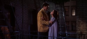 Movie still from “West Side Story” (1961), directed by Jerome Robbins – A man and a woman standing next to each other in front of a brick wall; Medium shot, Low angle