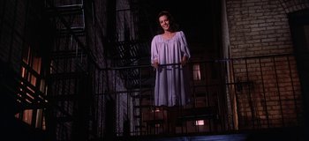Movie still from “West Side Story” (1961), directed by Jerome Robbins – A woman in a purple dress standing on stairs; Medium shot, Low angle
