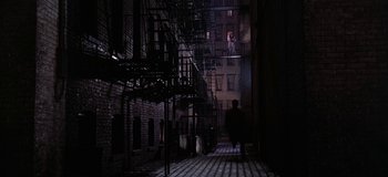 Movie still from “West Side Story” (1961), directed by Jerome Robbins – A man walking down a street near a fire escape; Extreme Wide shot, Low angle