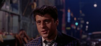 Movie still from “West Side Story” (1961), directed by Jerome Robbins – A person wearing a suit and tie; Close Up shot, Low angle
