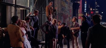 Movie still from “West Side Story” (1961), directed by Jerome Robbins – A group of men standing next to each other on a street; Wide shot, High angle
