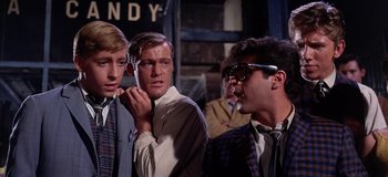 Movie still from “West Side Story” (1961), directed by Jerome Robbins – A group of young men standing next to each other on a street; Medium shot, Over the shoulder angle