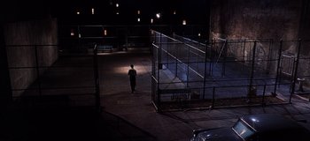 Movie still from “West Side Story” (1961), directed by Jerome Robbins – A person is walking in a parking lot at night; Extreme Wide shot, High angle