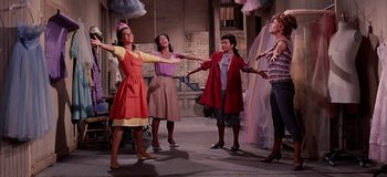 Movie still from “West Side Story” (1961), directed by Jerome Robbins – A group of women standing next to each other on a street; Wide shot, Low angle
