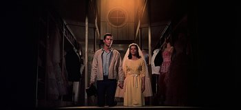 Movie still from “West Side Story” (1961), directed by Jerome Robbins – A man and a woman holding hands while standing on a train; Medium shot, Low angle