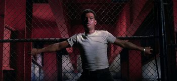 Movie still from “West Side Story” (1961), directed by Jerome Robbins – A man in white shirt and black pants standing in front of a fence; Medium shot, Low angle