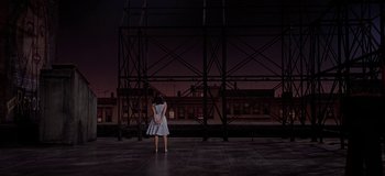 A woman standing in front of a building at night