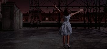 Movie still from “West Side Story” (1961), directed by Jerome Robbins – A woman in a dress standing on a concrete floor; Wide shot, Low angle