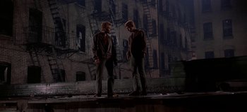 Movie still from “West Side Story” (1961), directed by Jerome Robbins – A couple of men standing next to each other on a street; Wide shot, Low angle